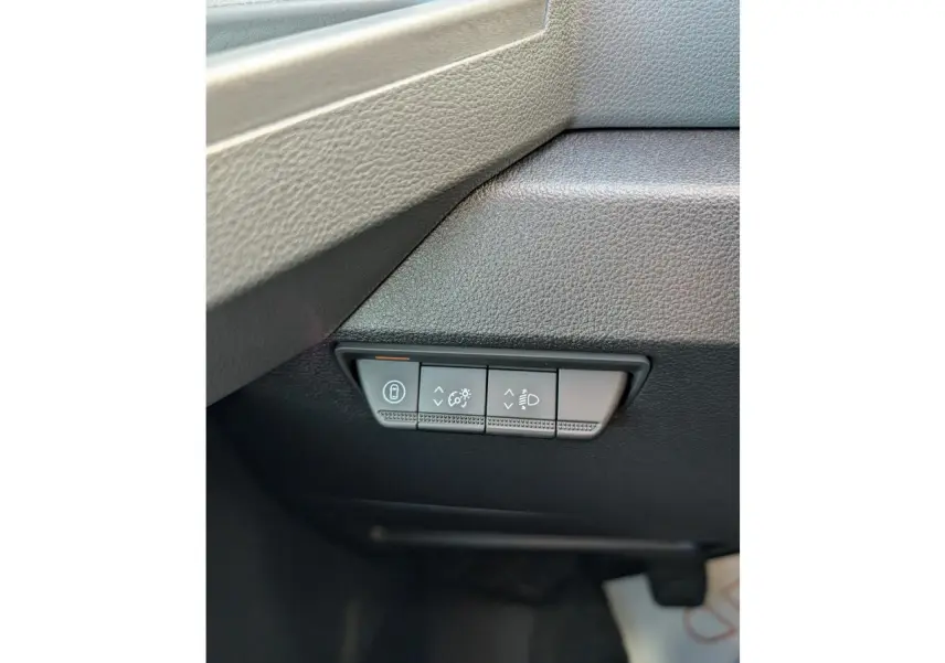 Gros plan sur les commandes de réglage des phares et du tableau de bord du Renault Master blanc 2025, côté gauche.