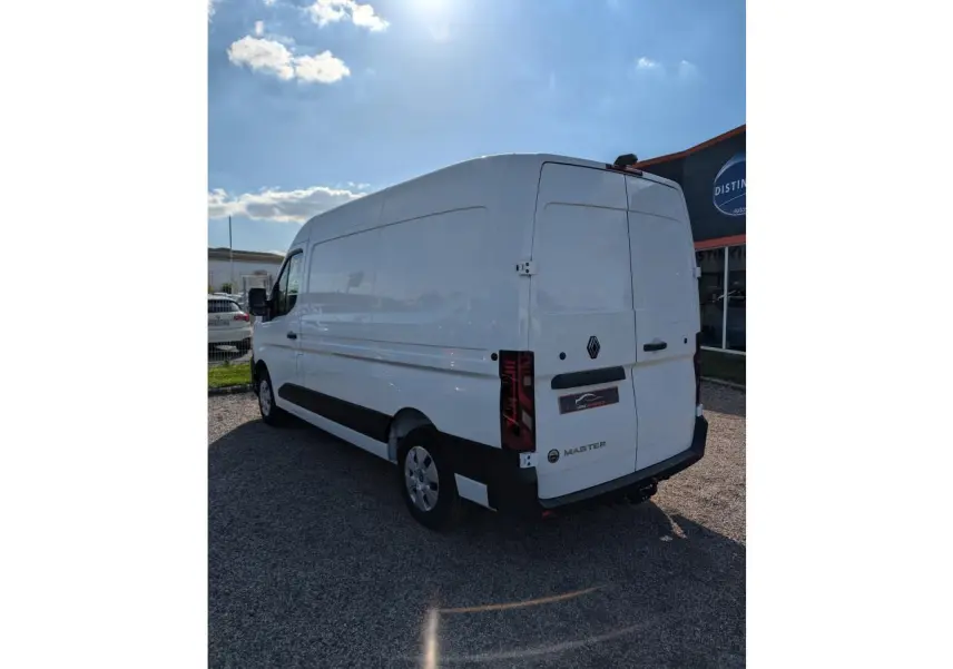 Renault Master blanc vu en 3/4 arrière droit, avec porte latérale coulissante et attelage visible.