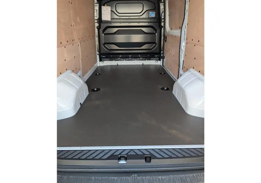 Intérieur du Renault Master 2025 vu de l'arrière, avec habillage bois latéral et plancher noir antidérapant.