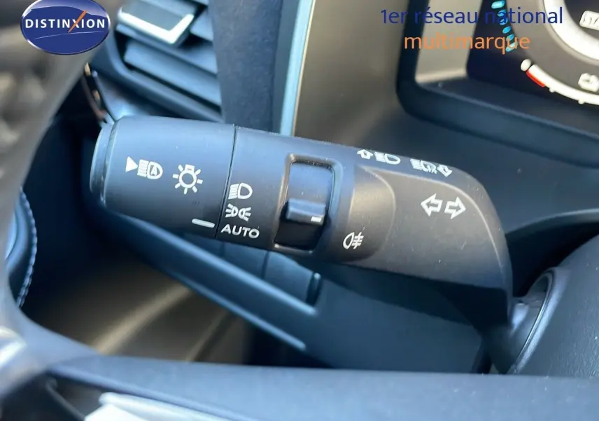 Gros plan sur la commande des phares et clignotants dans l'habitacle du Nissan Qashqai blanc nacré toit noir 2025.