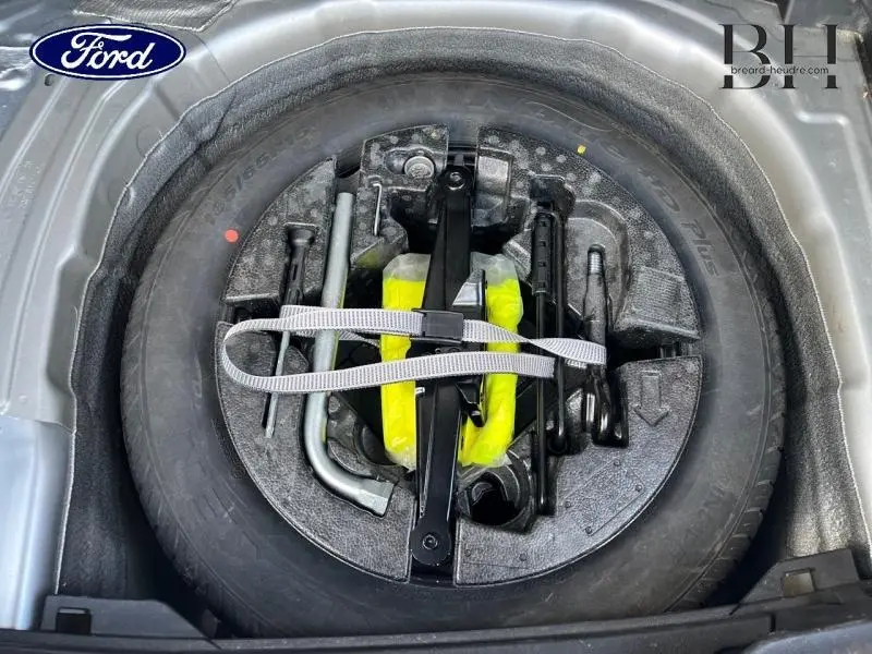 Gros plan sur la roue de secours à encombrement réduit et les outils de bord dans le coffre d'une Volkswagen Polo 2022 reflet d'argent métallisé.