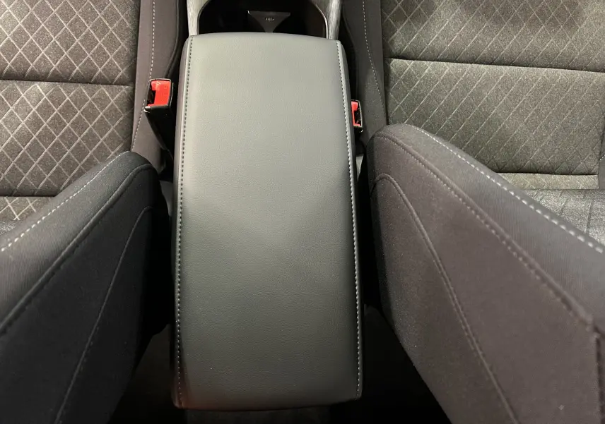 Vue plongeante sur l'accoudoir central en cuir noir entre les sièges tissu gris à motifs du MG ZS Cosmic Silver 2025.