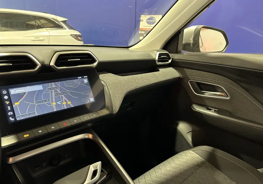 Vue intérieure côté passager du MG ZS 2025 avec tableau de bord noir, écran tactile GPS et sellerie tissu gris.