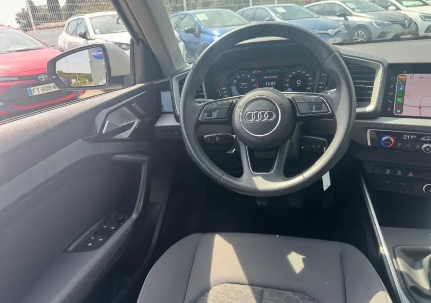 Vue intérieure avant de l'Audi A1 Sportback 2025 gris, volant cuir, cockpit numérique et écran tactile central visibles.