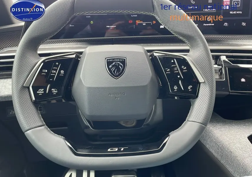 Volant cuir perforé avec logo Peugeot et inscription GT, tableau de bord numérique du 3008 Hybrid 145 GT e-THP 2025.