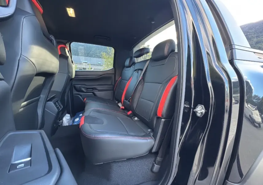 Vue intérieure côté droit du Ford Ranger Raptor 2024, sièges arrière noirs avec surpiqûres et inserts rouges.