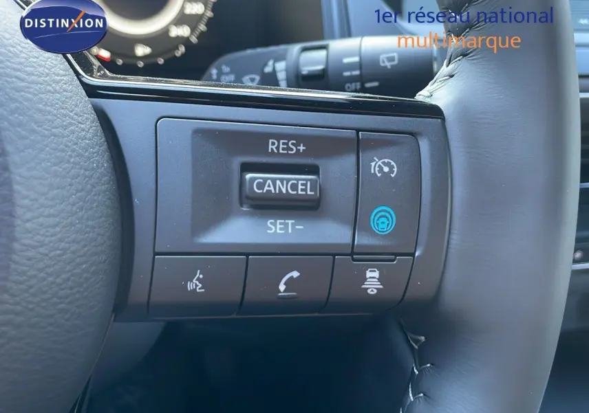 Gros plan sur les commandes au volant du Nissan Qashqai 2025 gris céramique avec toit noir, mettant en avant les boutons de régulateur de vitesse.