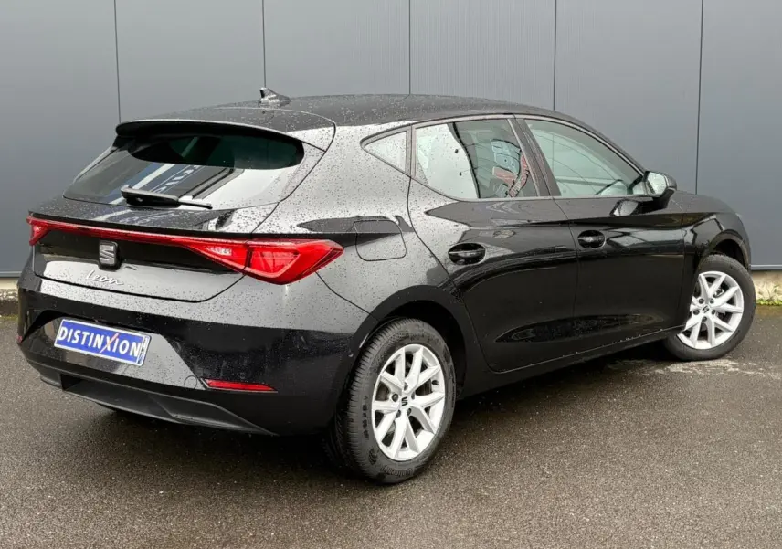 Vue 3/4 arrière droite d'une SEAT Leon 2024 noire Minuit avec jantes alliage 16 pouces sous la pluie.