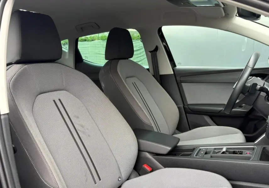 Vue intérieure côté droit montrant les sièges avant gris clair avec accoudoir central et volant cuir multifonction.