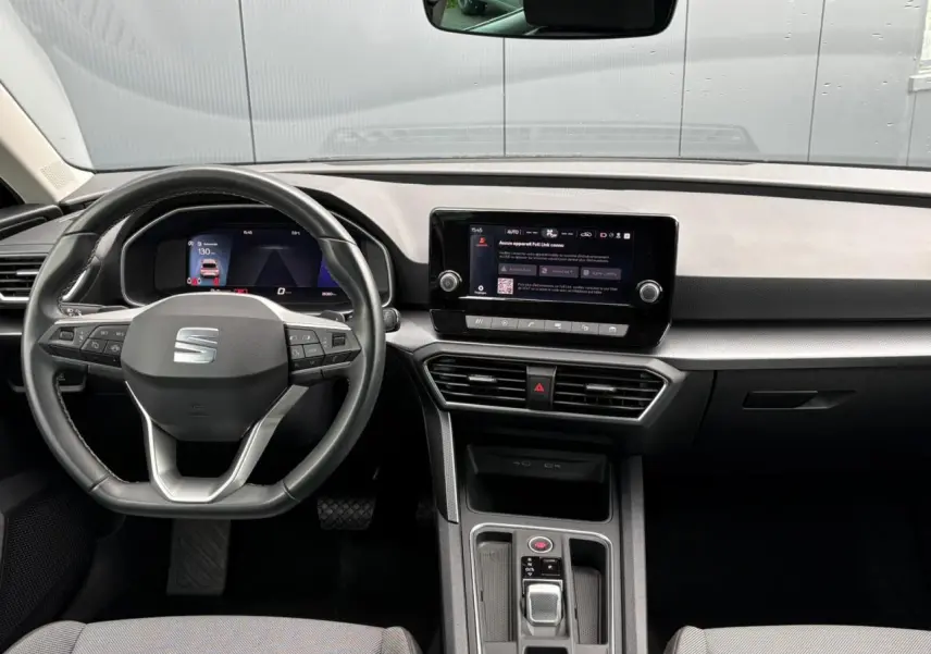 Vue intérieure avant du tableau de bord de la SEAT Leon 2024 avec volant cuir multifonction et écran tactile central.