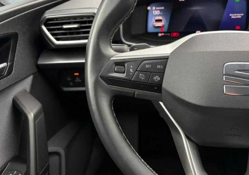Gros plan sur le volant cuir multifonction et le combiné digital noir du tableau de bord du SEAT Leon 2024.