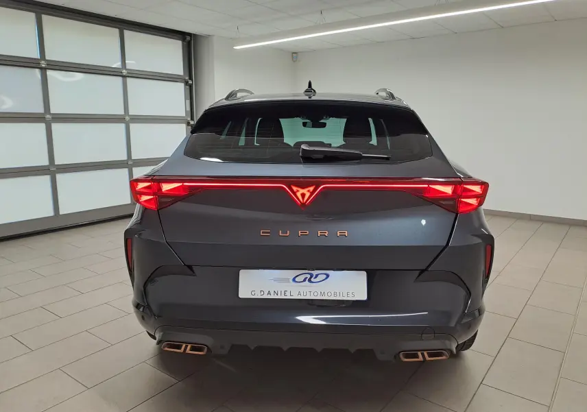 Vue arrière d'une CUPRA Formentor gris magnétique avec bandeau lumineux rouge et double sortie d'échappement cuivrée.