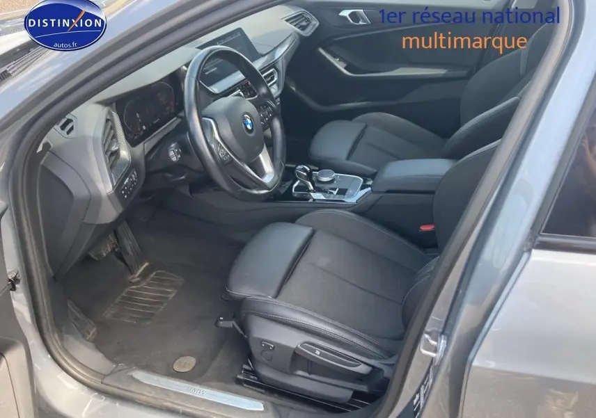 Intérieur côté conducteur d'une BMW Série 1 gris foncé, avec sièges sport noirs et tableau de bord moderne.