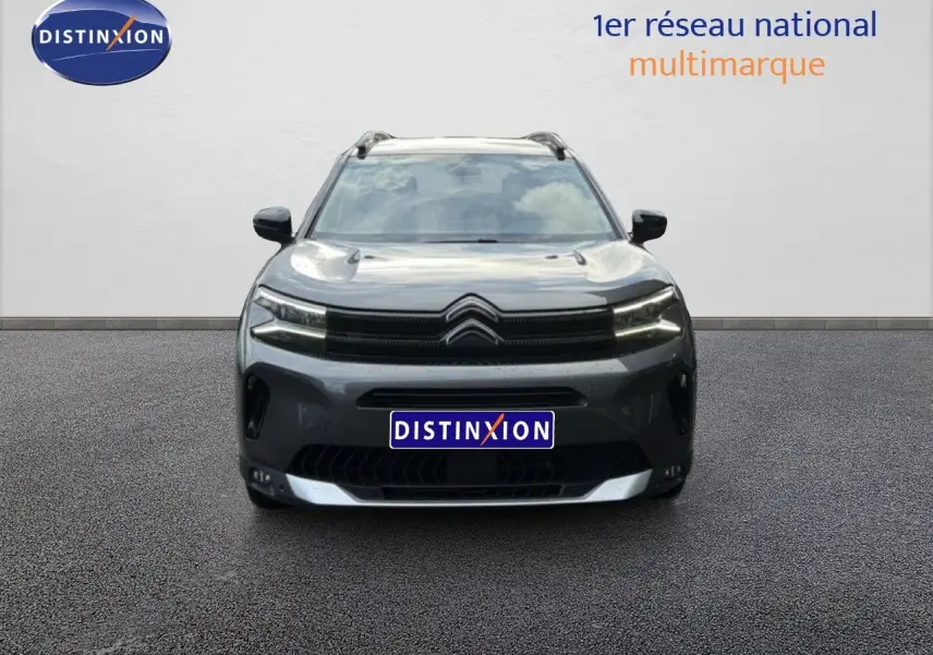 Vue avant d'un Citroën C5 Aircross gris platinium métal 2025 avec calandre noire et phares LED allumés.