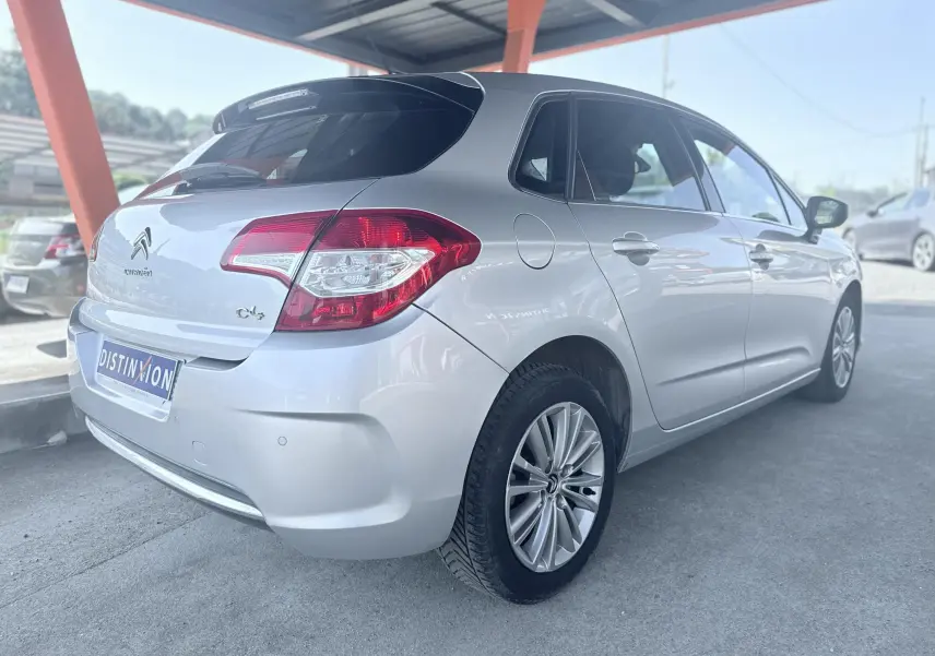 Vue 3/4 arrière droite d'une Citroën C4 gris clair, compacte cinq portes avec jantes alliage et feux arrière distinctifs.
