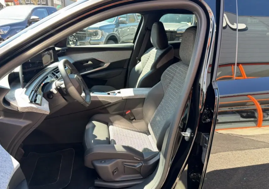 Vue intérieure côté conducteur du Peugeot 5008 Hybrid noir perla nera, sièges en cuir tissu avec réglages électriques visibles.