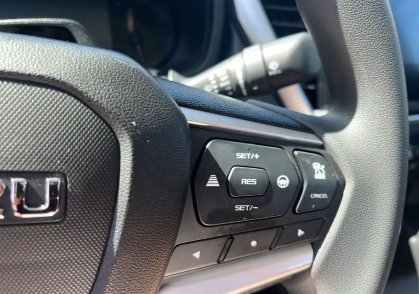 Gros plan sur le volant multifonctions noir de l'Isuzu D-MAX 2.2 TD 164 Space Evolution avec commandes de régulateur de vitesse.