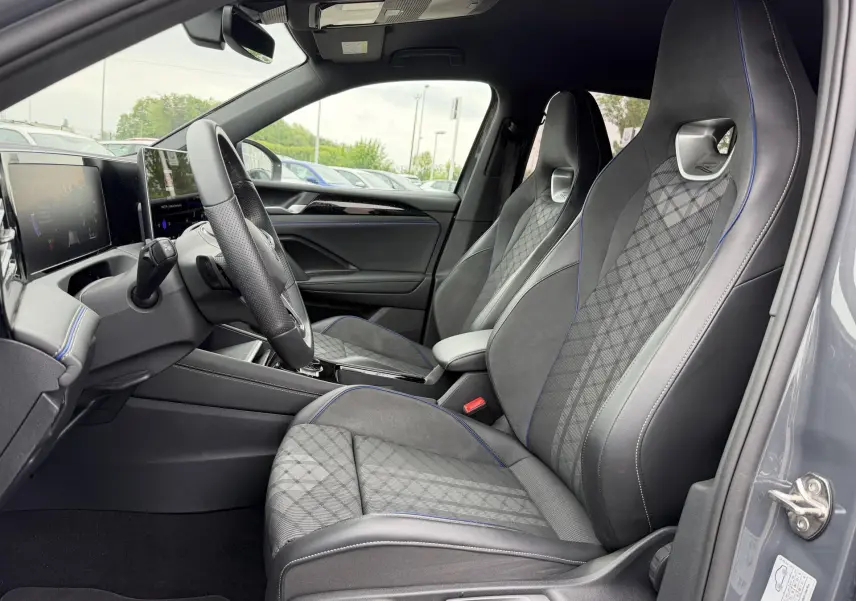 Intérieur côté conducteur du Volkswagen Tiguan gris 2025, sièges sport avec surpiqûres bleues et tableau de bord digital.