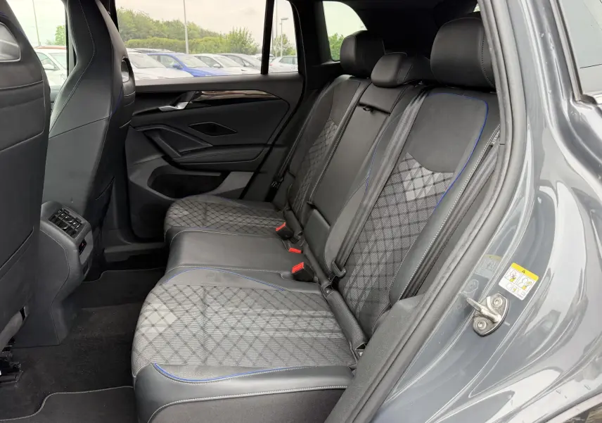 Vue intérieure côté droit des sièges arrière gris avec surpiqûres bleues du Volkswagen Tiguan 2025, porte ouverte.