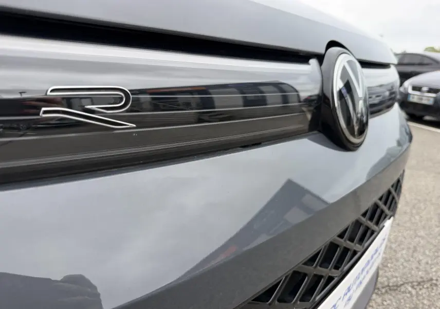 Gros plan sur la calandre avant grise du Volkswagen Tiguan avec logo VW et badge R visible.