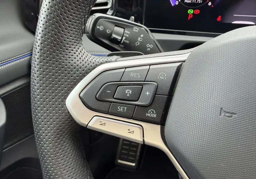 Gros plan sur le volant cuir perforé côté gauche du Volkswagen Tiguan 2025 avec commandes de régulateur adaptatif.