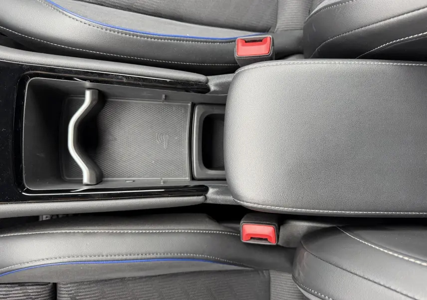 Vue plongeante sur la console centrale noire et les sièges gris avec surpiqûres bleues du Volkswagen Tiguan 2025.