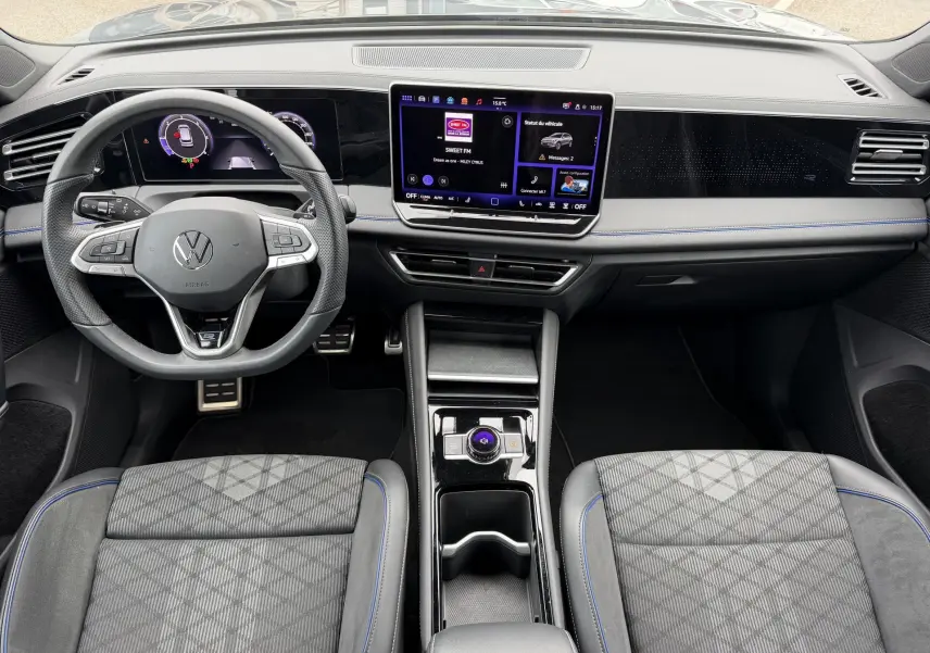 Vue intérieure du Volkswagen Tiguan 2025 montrant le tableau de bord noir avec écran tactile central et volant multifonction cuir.