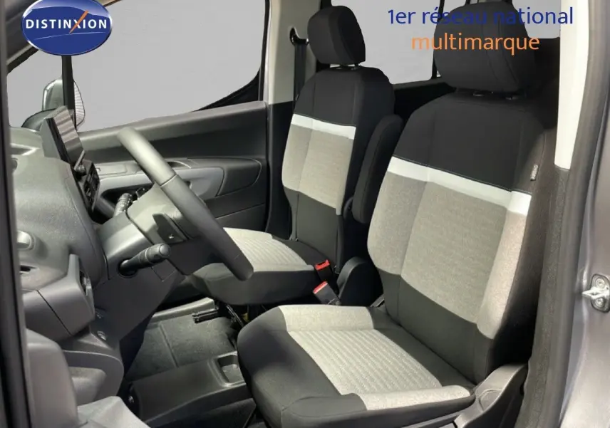 Vue intérieure côté conducteur du Citroën Berlingo gris Artense, sièges tissu bicolores avec bande blanche distinctive.