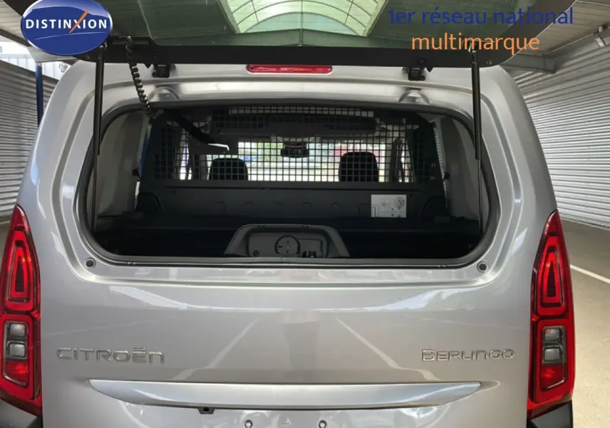 Vue arrière du Citroën Berlingo gris Artense métal avec hayon ouvert et grille de séparation visible à l'intérieur.