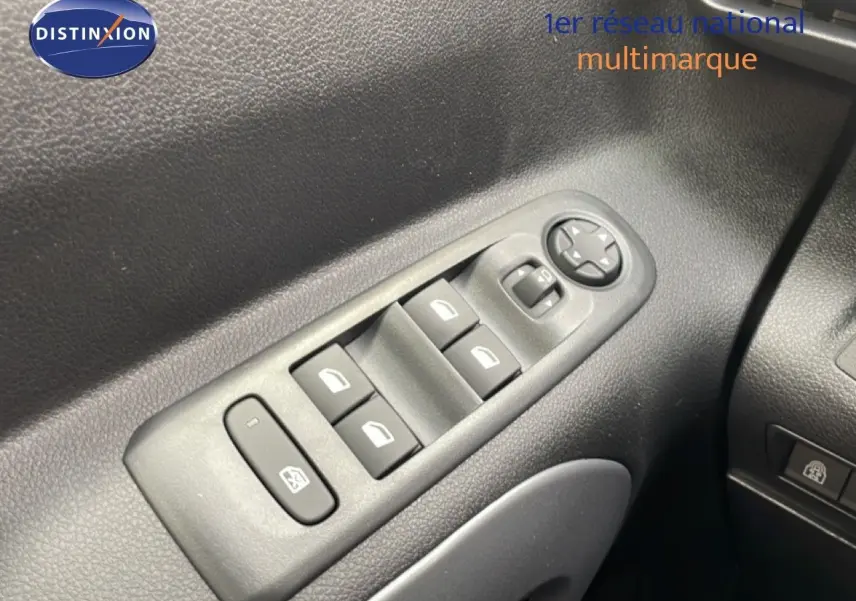 Gros plan sur les commandes des vitres électriques côté gauche du Citroën Berlingo gris Artense 2026.