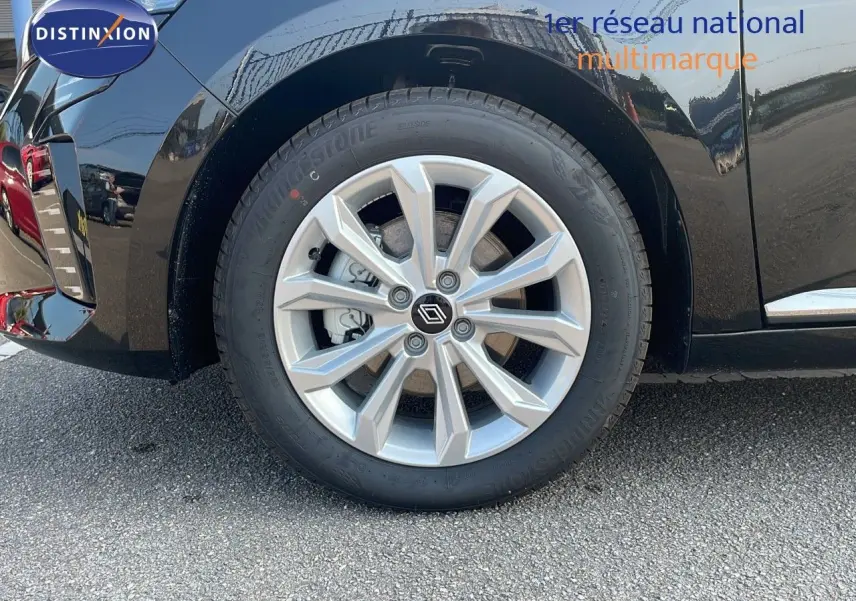 Gros plan sur la roue arrière gauche d'une Renault Clio 1.5 DCI noire étoile métal avec jante alliage moderne.