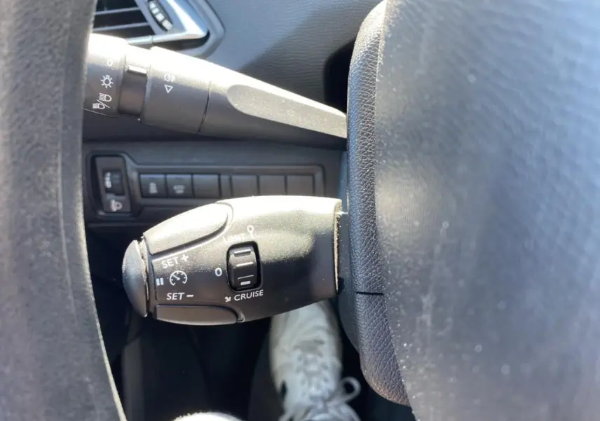 Gros plan sur la commande de régulateur de vitesse à gauche du volant dans l'habitacle d'une Peugeot 308 SW.