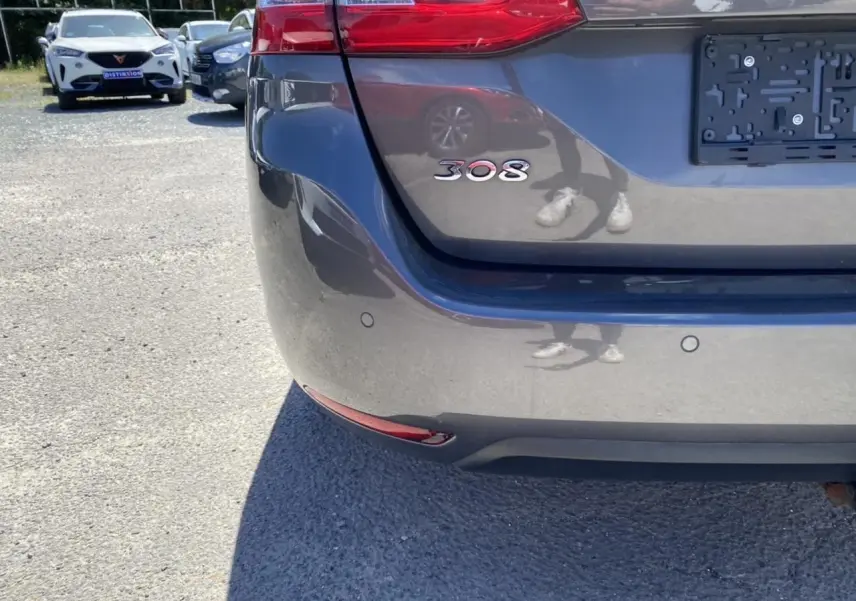 Gros plan sur l'arrière gris clair d'une Peugeot 308 SW 2017 avec logo 308 et capteurs de stationnement visibles.