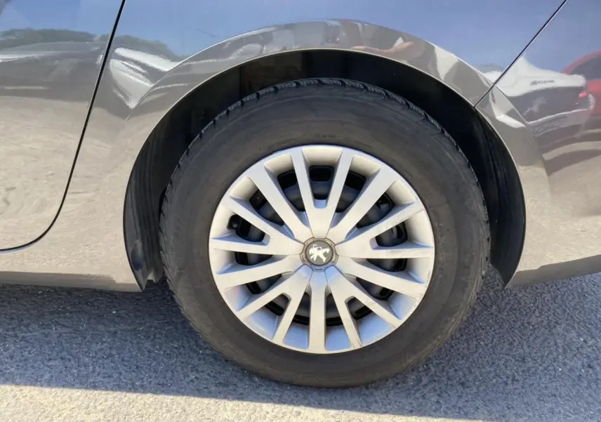 Gros plan sur la roue arrière droite gris clair d'une Peugeot 308 SW 1.6 BlueHDi de 2017 avec jante en alliage.