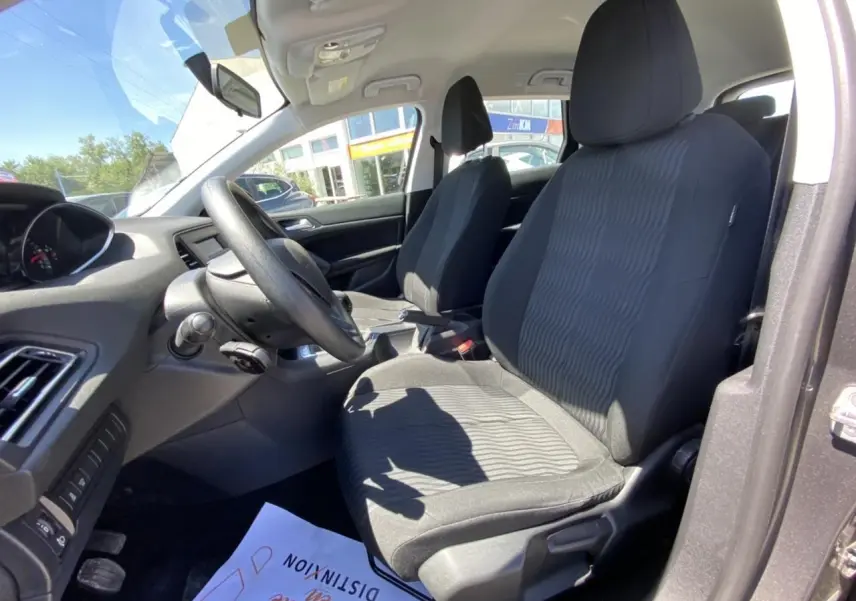 Intérieur avant droit de la Peugeot 308 SW 2017, sièges tissu noir et tableau de bord visible au soleil.