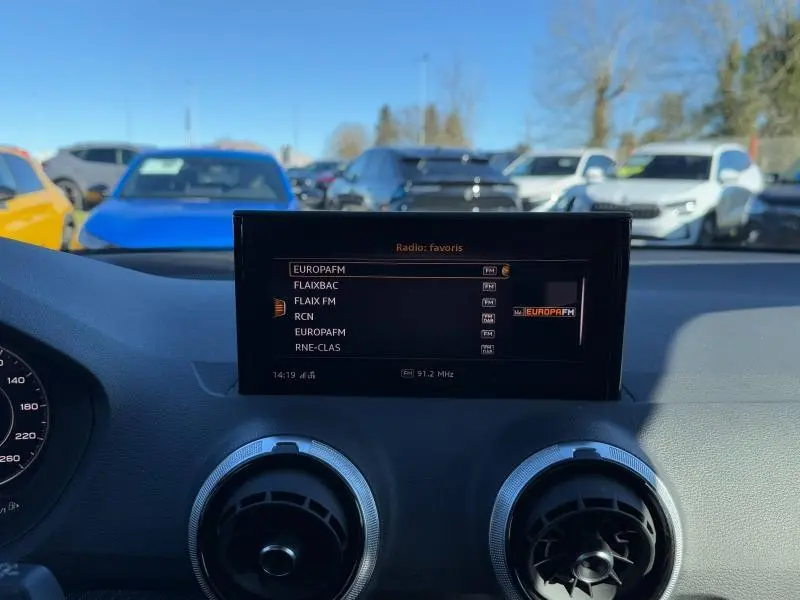 Vue intérieure du tableau de bord de l'Audi Q2 30 TDI 2024, écran multimédia affichant les radios favorites.