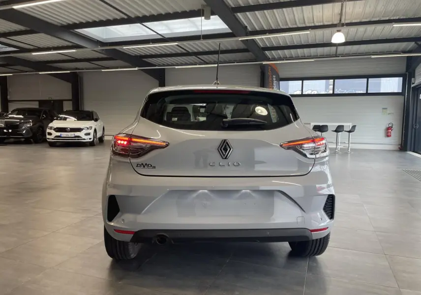 Vue arrière d'une Renault Clio 1.5 Blue dCi 2025 gris Rafale en intérieur avec feux arrière allumés.