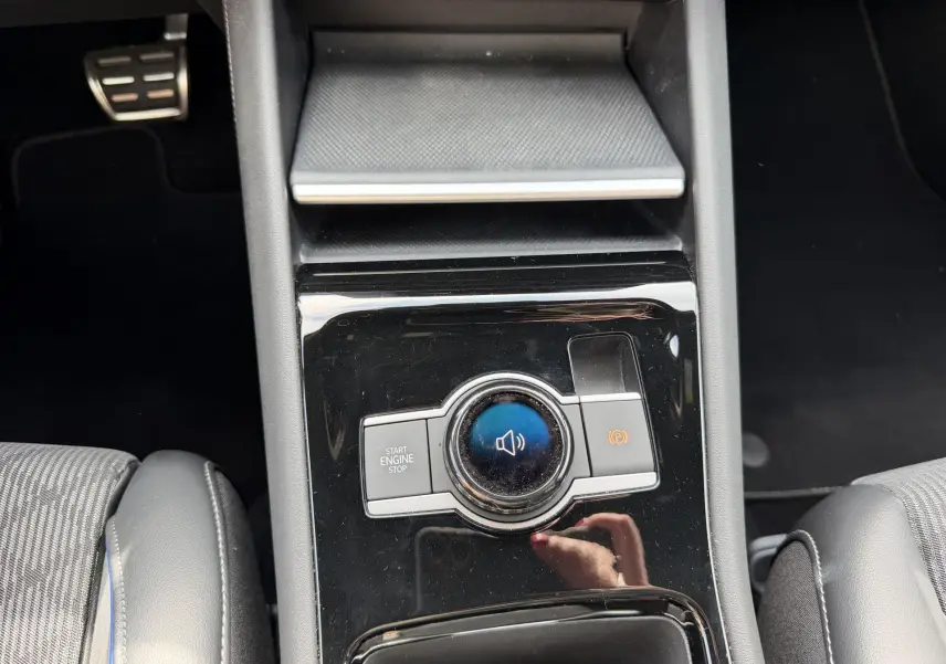 Vue rapprochée de la console centrale noire du Volkswagen Tiguan 2025 avec bouton Start/Stop et frein à main électronique.