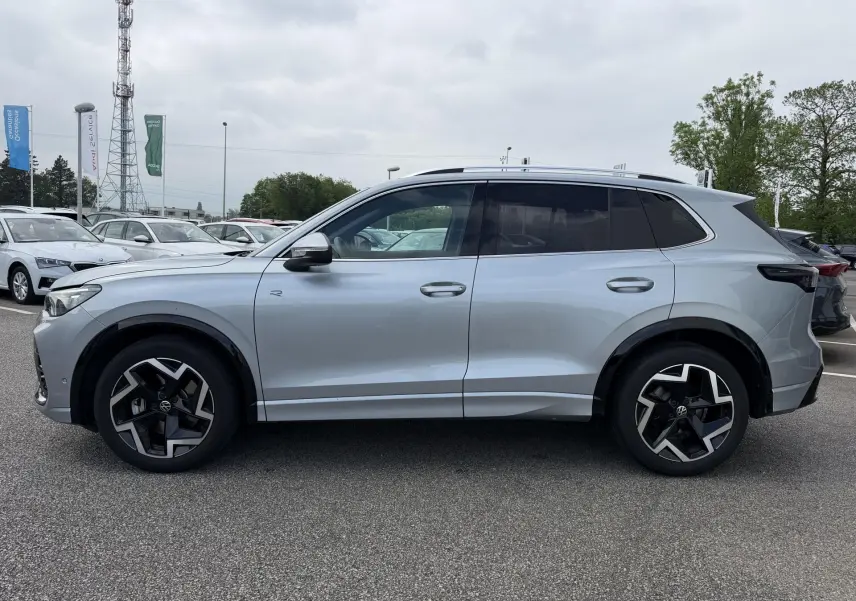 Vue de profil côté gauche d'un Volkswagen Tiguan gris 2025 avec jantes alliage noires et pack R-Line extérieur.
