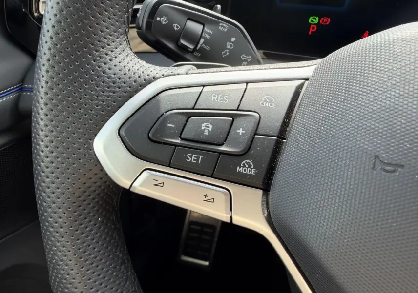 Gros plan sur les commandes du volant cuir perforé du Volkswagen Tiguan 2025 avec boutons de régulateur de vitesse.