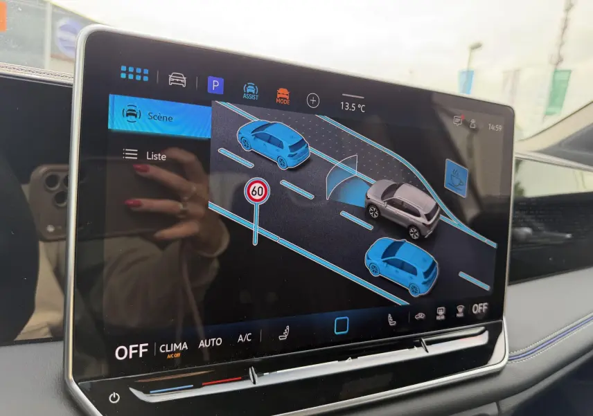 Écran tactile intérieur du Volkswagen Tiguan 2025 montrant l’aide au stationnement avec véhicules et signalisation virtuelle.