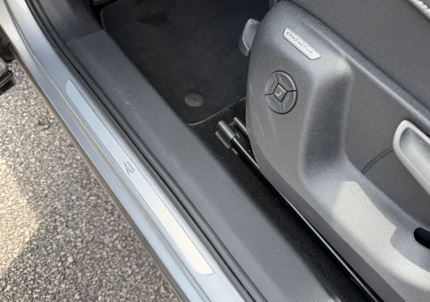 Détail de la porte côté gauche d’un Volkswagen Tiguan gris, avec siège ErgoActive et seuil de porte R-Line.