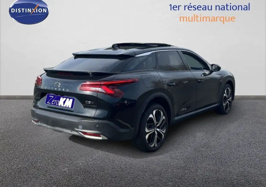 Vue 3/4 arrière droite d'une Citroën C5 X noire métallisée 2023 avec toit panoramique et jantes bicolores.