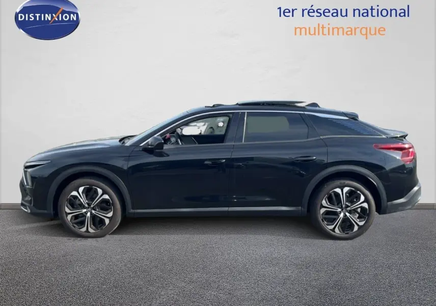 Profil côté gauche d'une Citroën C5 X noire métal 2023 avec jantes bi-ton et toit panoramique ouvert.