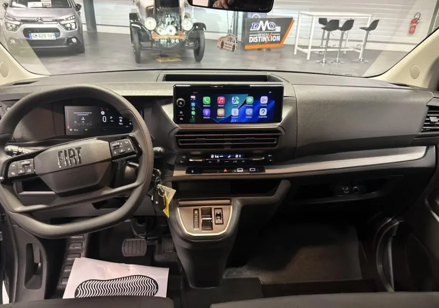 Vue intérieure avant du tableau de bord gris foncé du Fiat Scudo Fourgon XL 2026 avec écran tactile central et volant multifonction.