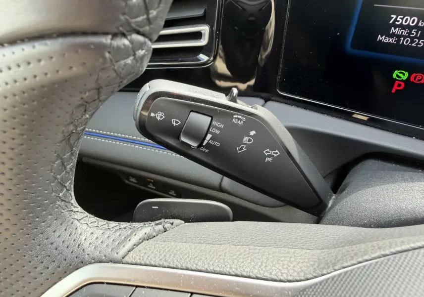 Gros plan sur la manette de commandes des essuie-glaces à gauche du volant noir perforé dans l’habitacle gris du Volkswagen Tiguan 2025.