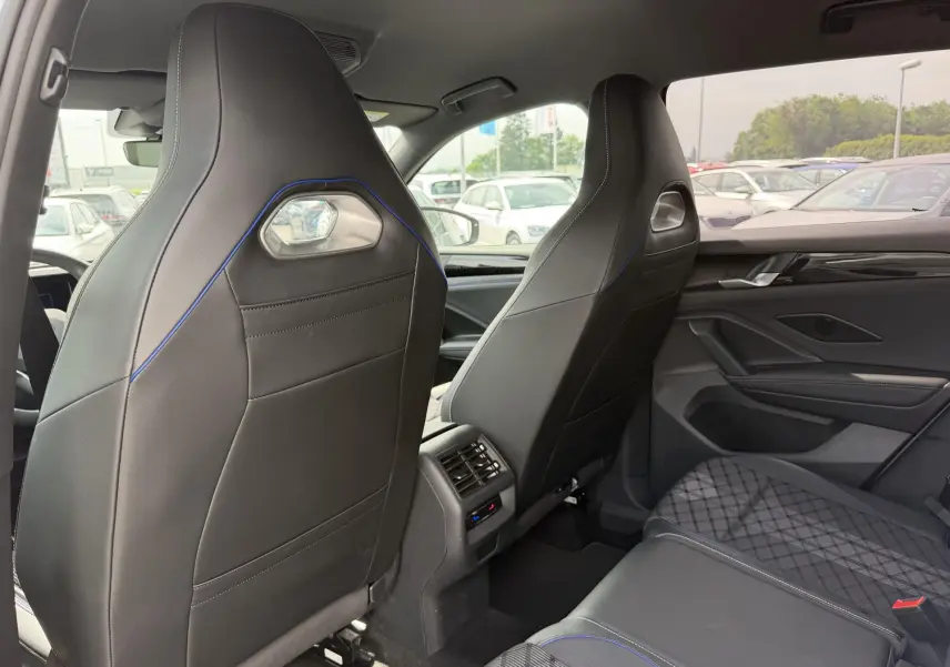 Vue arrière des sièges avant en cuir noir avec surpiqûres bleues et banquette arrière tissu gris à motifs dans un Volkswagen Tiguan gris.