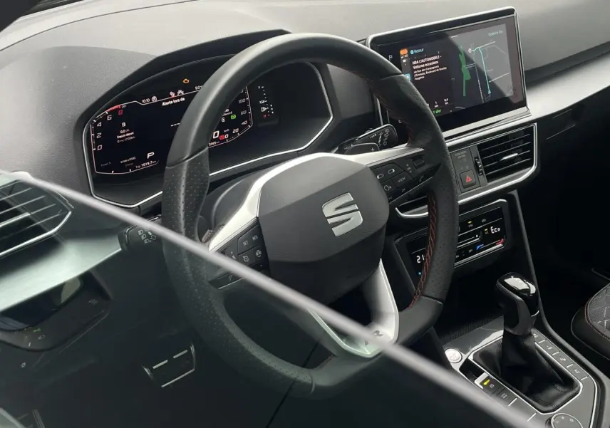 Intérieur du SEAT Tarraco 2024, vue du poste de conduite avec volant sport et écran tactile de navigation.