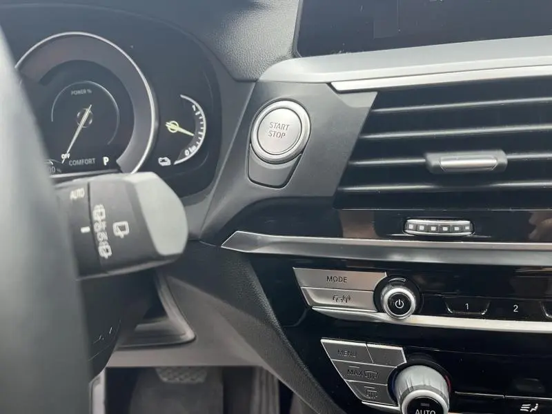 Détail intérieur côté gauche du tableau de bord noir du BMW X3 xDrive30e avec bouton Start/Stop et commandes multimédia.