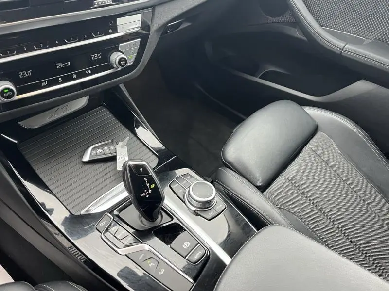 Intérieur noir du BMW X3 xDrive30e 2020, vue sur la console centrale avec levier de vitesses et siège passager en tissu.